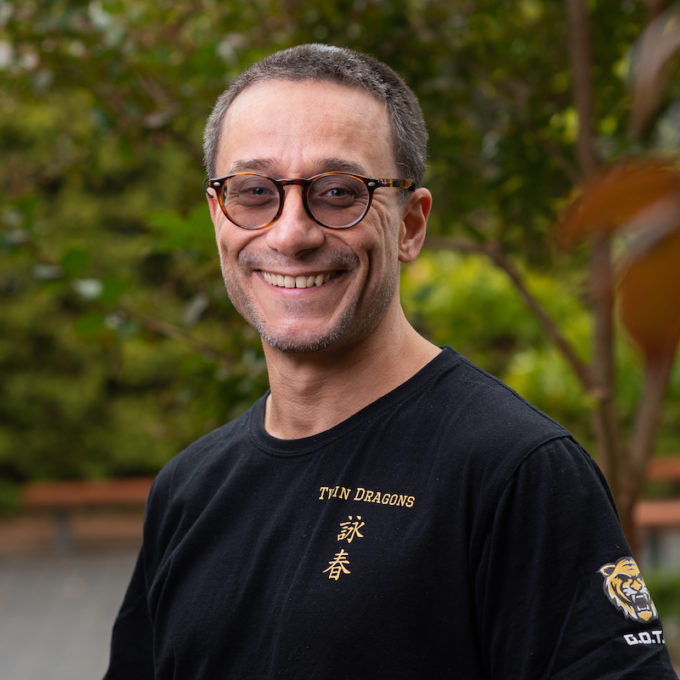 Kung-Fu Teacher Nick Bennett standing wearing a black t-shirt and glasses, smiling.